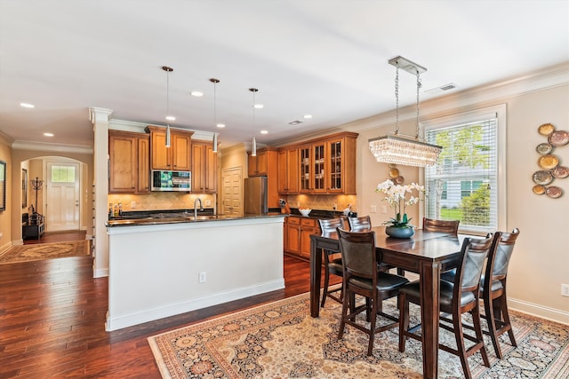 dining area with ornamental molding, arched walkways, baseboards, dark wood-style floors, and recessed lighting