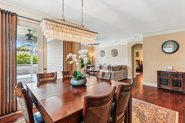 dining room featuring arched walkways, ornamental molding, ceiling fan, dark wood-type flooring, and baseboards