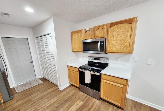 kitchen with light hardwood / wood-style flooring, stainless steel appliances, and a textured ceiling