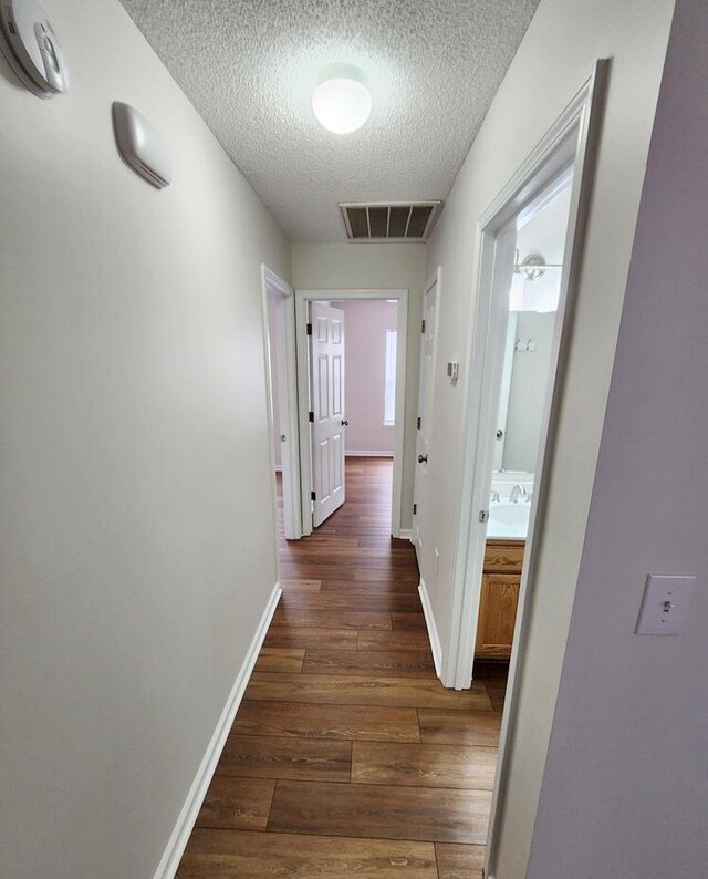 hall featuring a textured ceiling and dark wood-type flooring