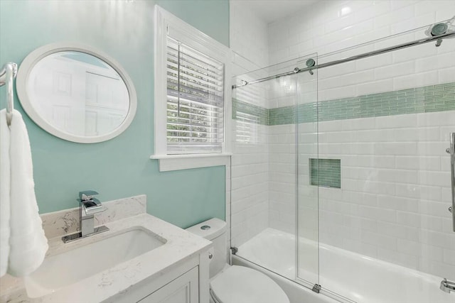 full bathroom featuring toilet, vanity, and shower / bath combination with glass door