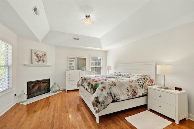 bedroom featuring a raised ceiling, multiple windows, and hardwood / wood-style flooring