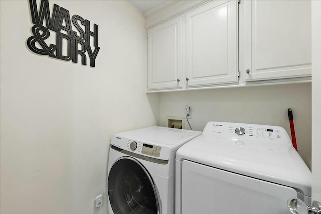 washroom with washer and dryer and cabinets