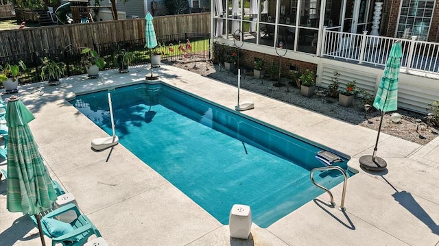 view of swimming pool with a sunroom and a patio