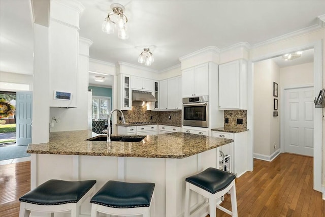 kitchen featuring white cabinets, backsplash, kitchen peninsula, and appliances with stainless steel finishes