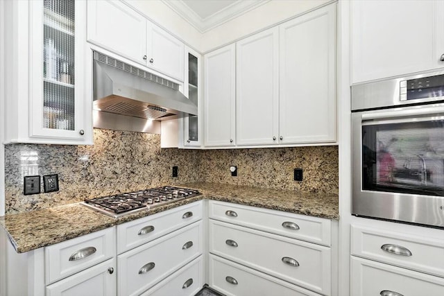 kitchen featuring backsplash, stainless steel appliances, ornamental molding, white cabinets, and ventilation hood