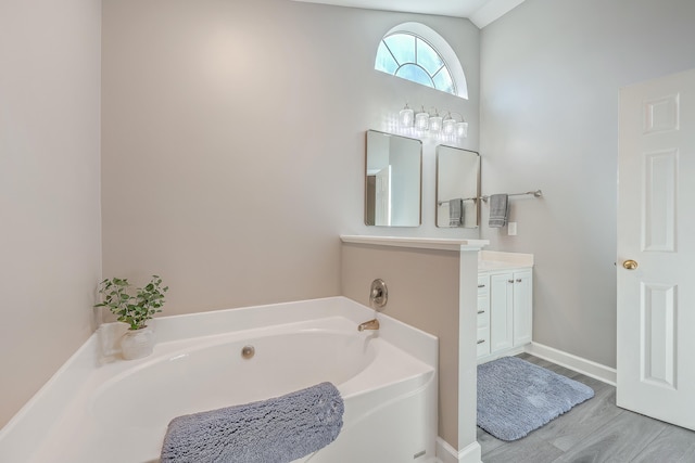 bathroom featuring vanity, vaulted ceiling, and a tub to relax in