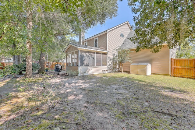 rear view of house featuring a sunroom and a yard