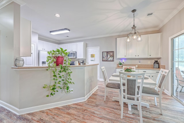 dining space featuring ornamental molding, a chandelier, and light wood-type flooring