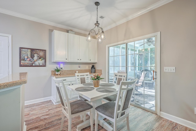 dining space with crown molding, an inviting chandelier, and light hardwood / wood-style floors