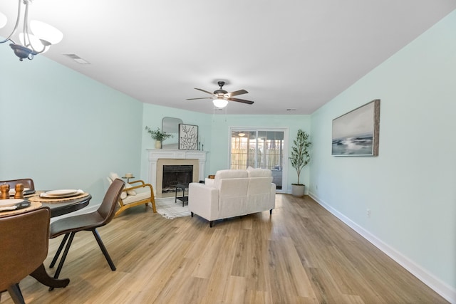 living room with light hardwood / wood-style flooring and ceiling fan with notable chandelier