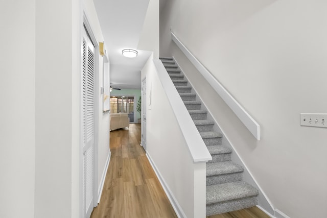 staircase with hardwood / wood-style floors and ceiling fan