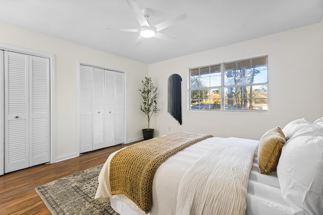 bedroom with ceiling fan, wood-type flooring, and two closets