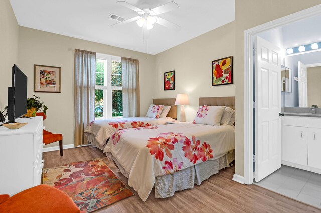 bedroom featuring ensuite bath, sink, light wood-type flooring, and ceiling fan