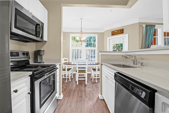 kitchen with sink, appliances with stainless steel finishes, pendant lighting, and white cabinetry