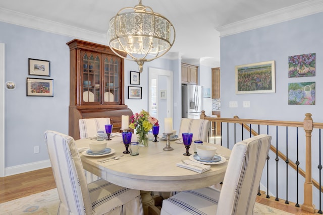 dining room featuring ornamental molding, a notable chandelier, and light hardwood / wood-style flooring