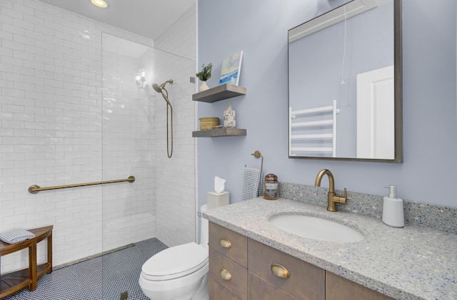 bathroom featuring vanity, a tile shower, and toilet