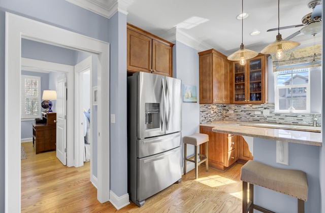 kitchen featuring hanging light fixtures, stainless steel fridge with ice dispenser, light stone countertops, a kitchen bar, and decorative backsplash