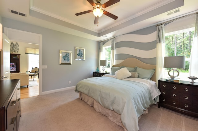 carpeted bedroom with a tray ceiling, multiple windows, and ceiling fan