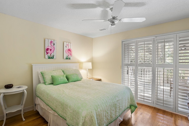 bedroom with hardwood / wood-style flooring, ceiling fan, and a textured ceiling