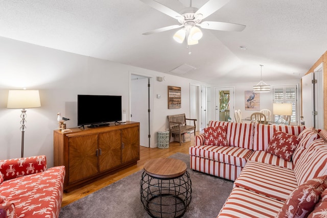 living room with dark wood-type flooring, vaulted ceiling, a textured ceiling, and ceiling fan