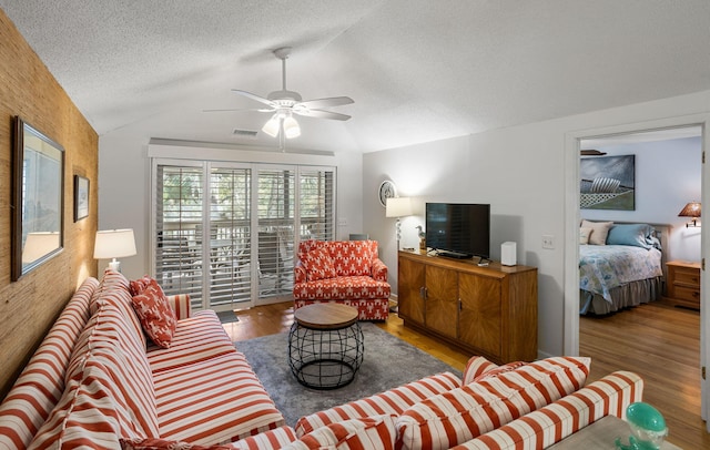 living room featuring lofted ceiling, wood-type flooring, a textured ceiling, and ceiling fan