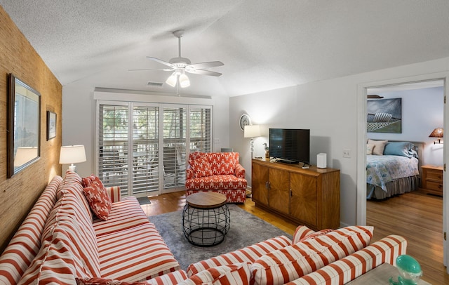 living room with wood finished floors, ceiling fan, vaulted ceiling, and a textured ceiling