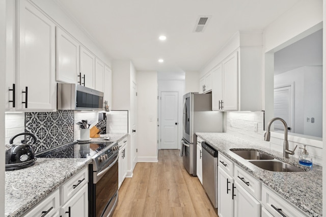 kitchen with white cabinets, sink, light hardwood / wood-style flooring, light stone countertops, and stainless steel appliances