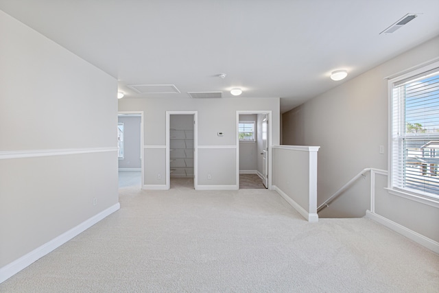 unfurnished room with light carpet, visible vents, and baseboards