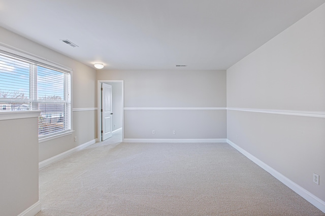 spare room with visible vents, light carpet, and baseboards