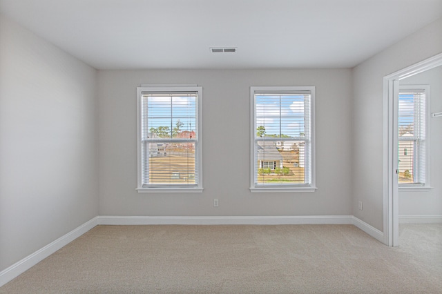 empty room featuring light carpet, visible vents, and baseboards