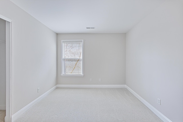 empty room featuring baseboards, visible vents, and light colored carpet