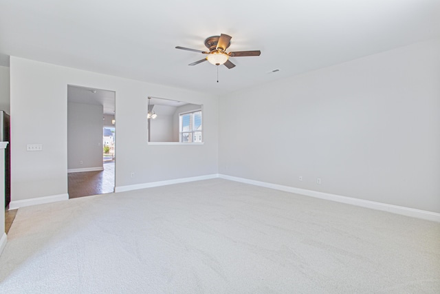 carpeted spare room featuring visible vents, baseboards, and a ceiling fan