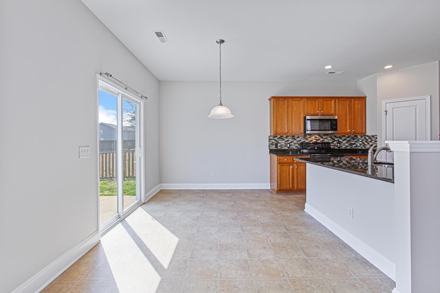 kitchen featuring stove, visible vents, baseboards, backsplash, and stainless steel microwave