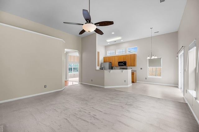 1445 Ashley Gardens Blvd, Charleston, SC 29414 - unfurnished living room with light carpet, ceiling fan, a chandelier, a high ceiling, and arched walkways
