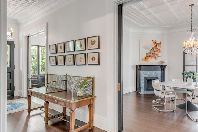 home office with wood-type flooring, an inviting chandelier, a brick fireplace, and crown molding