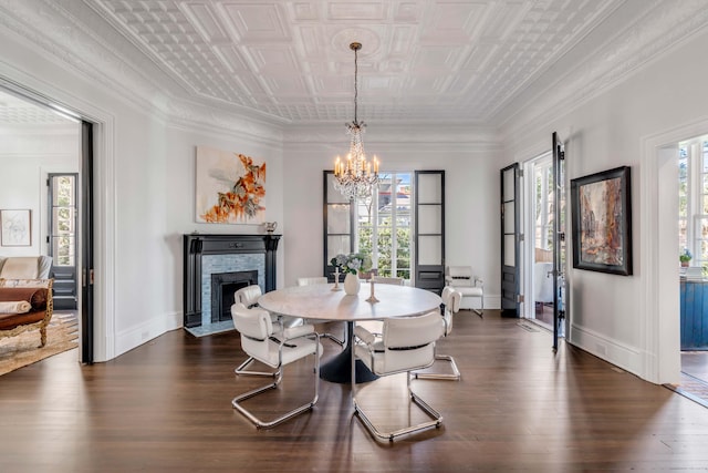 dining area with a chandelier, dark hardwood / wood-style floors, a brick fireplace, and a healthy amount of sunlight