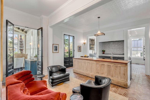 living room featuring ornamental molding, a healthy amount of sunlight, and sink