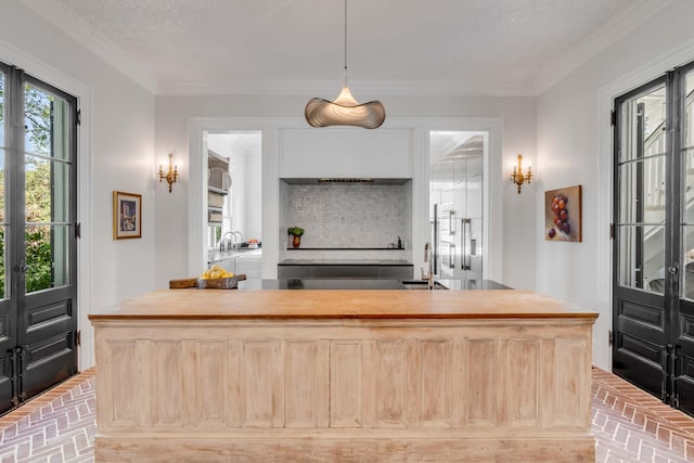 kitchen with pendant lighting, crown molding, sink, an island with sink, and a textured ceiling