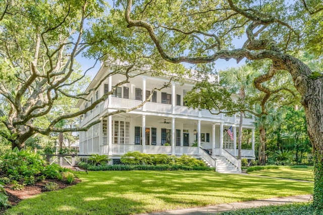 view of front facade with ceiling fan, a balcony, a front lawn, and covered porch