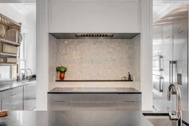 kitchen featuring black electric stovetop, backsplash, premium range hood, and sink