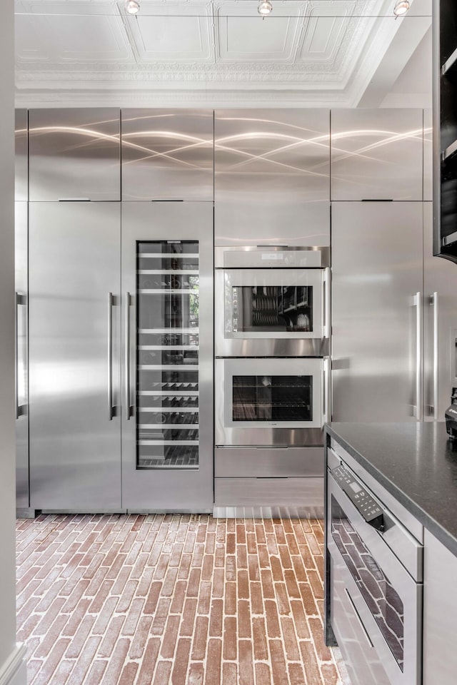 kitchen with stainless steel double oven, dark stone counters, and crown molding