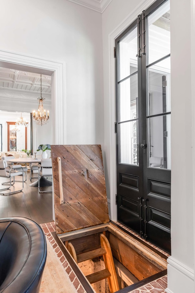 foyer with french doors, crown molding, a wealth of natural light, and a chandelier