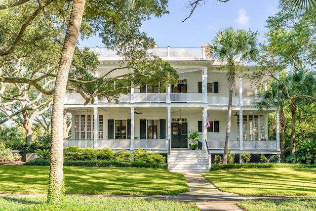 view of front of home with a porch, a balcony, a front lawn, and ceiling fan