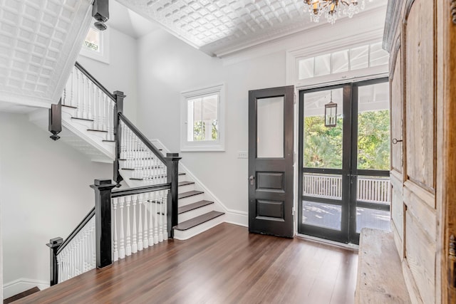 entryway featuring a chandelier, dark hardwood / wood-style flooring, crown molding, and french doors