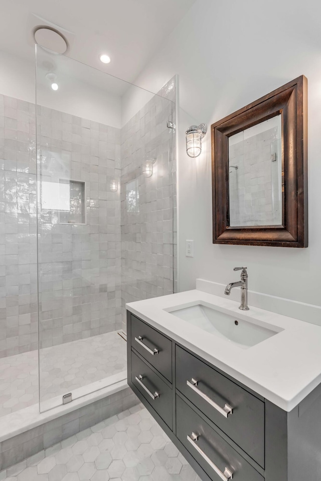 bathroom featuring tile patterned flooring, vanity, and a tile shower