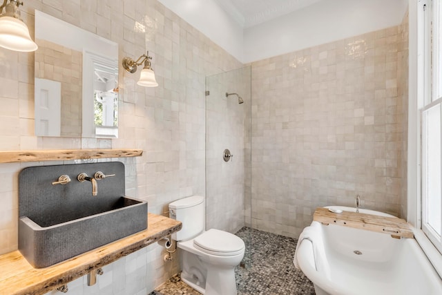 bathroom featuring toilet, a tile shower, and tile walls