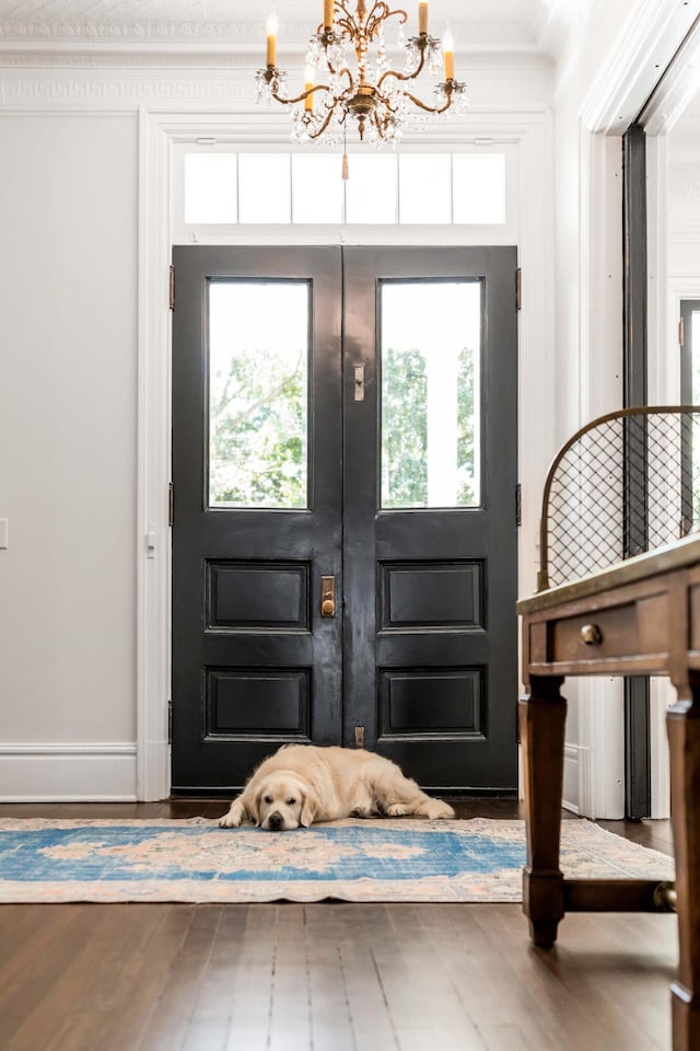 entryway featuring hardwood / wood-style flooring, crown molding, and an inviting chandelier