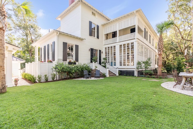 back of house with a lawn and a balcony