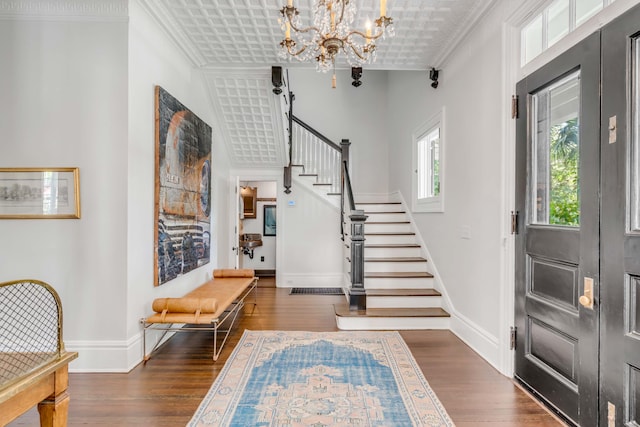 entryway with a notable chandelier, dark hardwood / wood-style floors, and ornamental molding